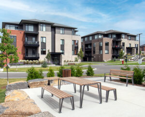 Benches and a picnic table in a park area in front of a building at Richardson Ridge, a residential community in Ottawa.